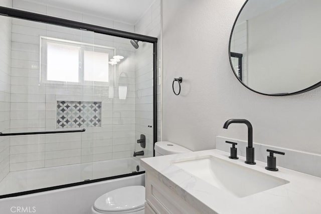 full bathroom featuring vanity, toilet, and shower / bath combination with glass door