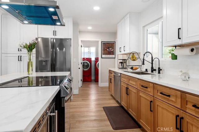 kitchen with a sink, decorative backsplash, appliances with stainless steel finishes, exhaust hood, and washer and clothes dryer