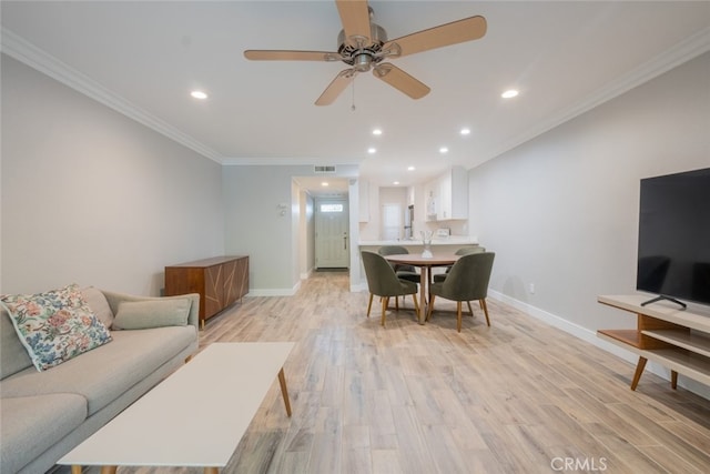 living area featuring baseboards, light wood-style floors, visible vents, and ornamental molding