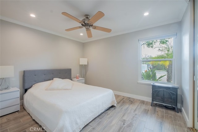 bedroom featuring light wood finished floors, crown molding, a wood stove, and baseboards