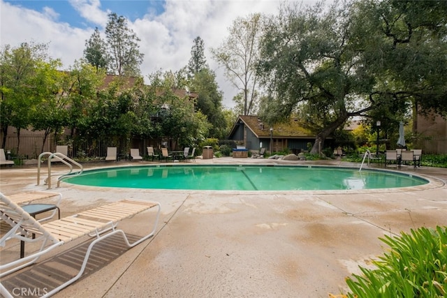 community pool with a patio area and fence