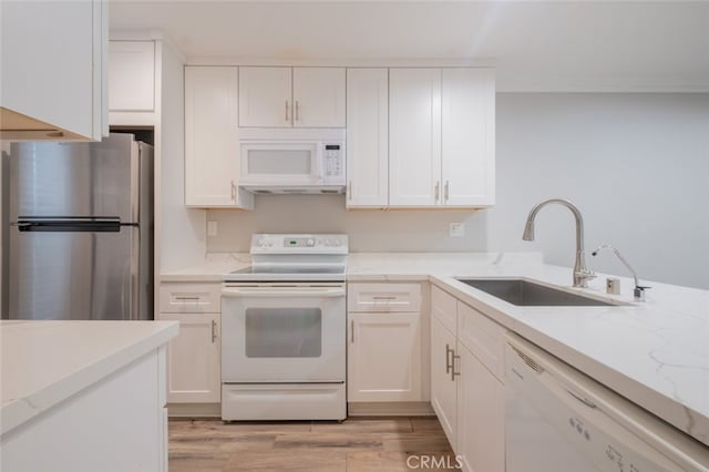 kitchen with light stone countertops, light wood-type flooring, white cabinets, white appliances, and a sink