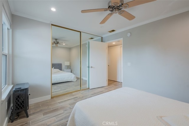 bedroom featuring baseboards, visible vents, light wood-style flooring, a closet, and crown molding