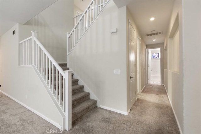 stairway with baseboards, visible vents, and carpet floors