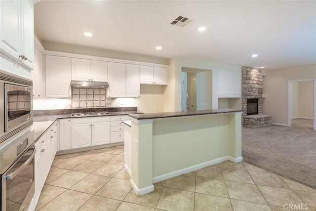 kitchen featuring visible vents, stainless steel appliances, under cabinet range hood, white cabinetry, and dark countertops