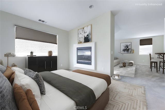 bedroom featuring visible vents, a glass covered fireplace, and carpet floors