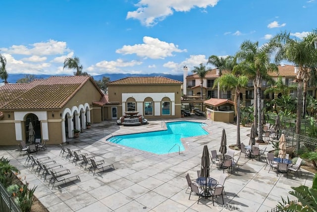 community pool with a patio area and fence