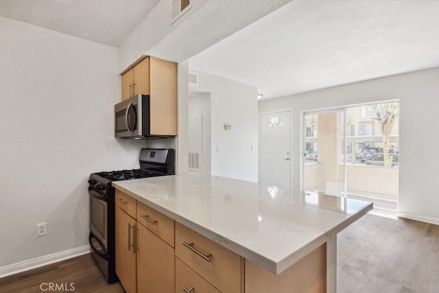 kitchen featuring visible vents, dark wood-type flooring, stainless steel microwave, gas stove, and a peninsula