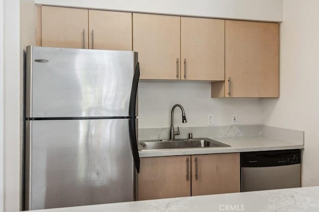 kitchen featuring light countertops, light brown cabinets, appliances with stainless steel finishes, and a sink