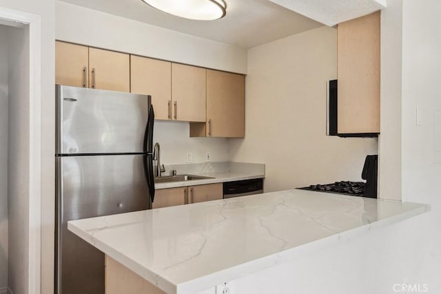 kitchen featuring a sink, stainless steel appliances, light stone counters, and a peninsula