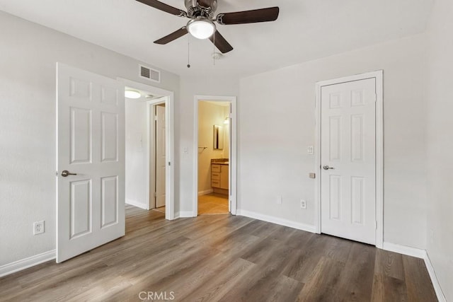 unfurnished bedroom with wood finished floors, visible vents, and baseboards