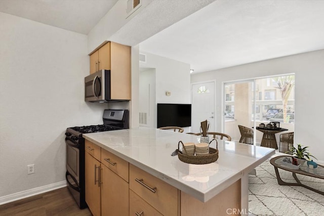 kitchen with black gas range oven, stainless steel microwave, visible vents, dark wood finished floors, and a peninsula