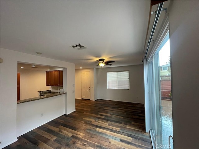 unfurnished living room with dark wood finished floors, baseboards, visible vents, and ceiling fan