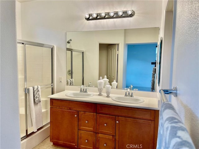 full bathroom featuring a sink, double vanity, and a shower stall