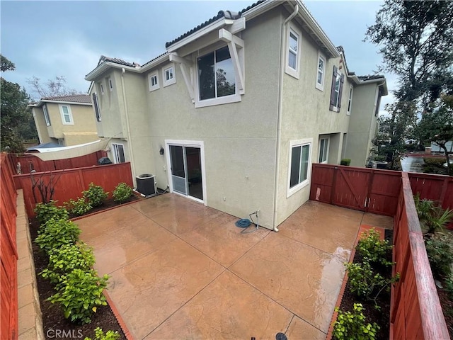 back of property with a patio, central AC unit, a fenced backyard, and stucco siding