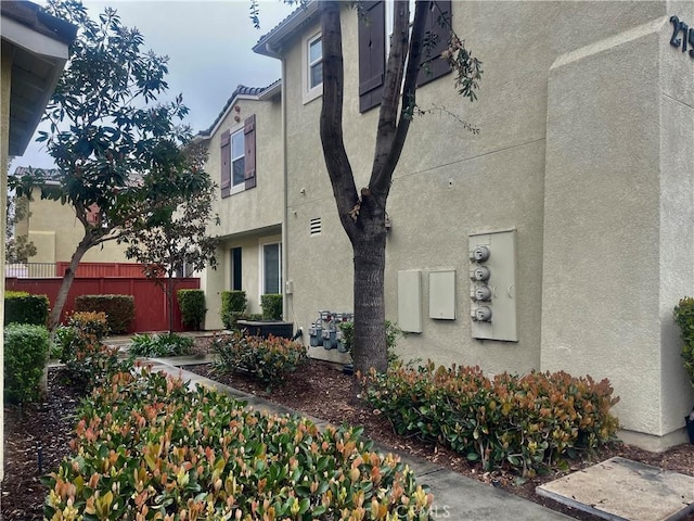 view of property exterior with stucco siding and fence