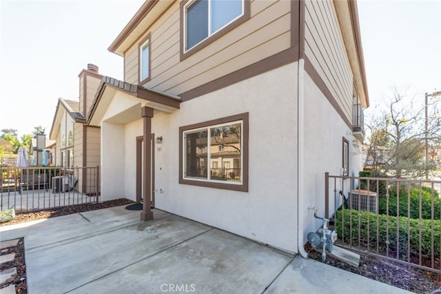 exterior space featuring a patio, central AC unit, fence, and stucco siding