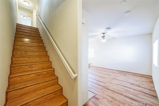 staircase featuring visible vents, wood finished floors, and ceiling fan