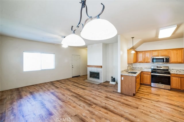 kitchen featuring a sink, stainless steel appliances, open floor plan, and light wood-style flooring