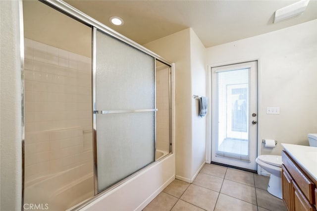 bathroom featuring tile patterned floors, toilet, enclosed tub / shower combo, baseboards, and vanity