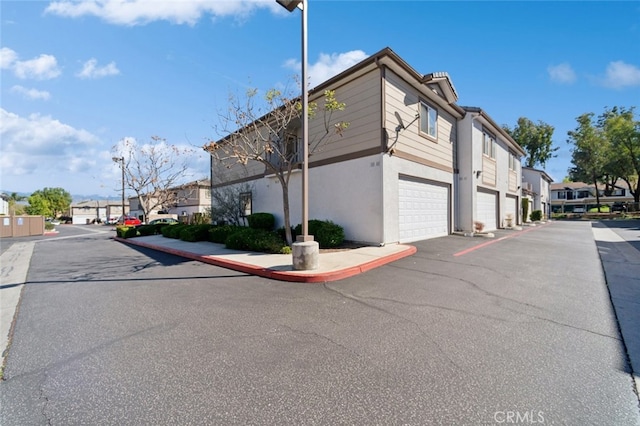 view of side of property with a residential view, stucco siding, and a garage