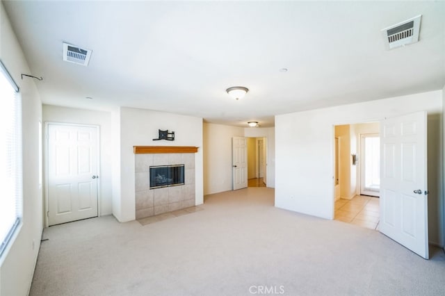 unfurnished living room featuring visible vents, carpet flooring, and a tile fireplace