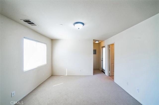 spare room with visible vents, light colored carpet, and a textured ceiling