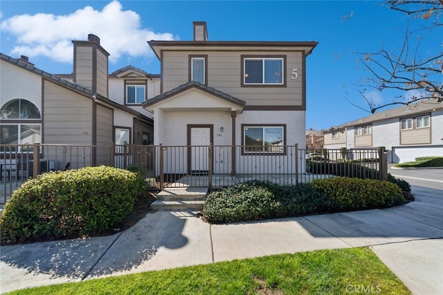 view of front of home featuring stucco siding, a gate, a fenced front yard, and a chimney