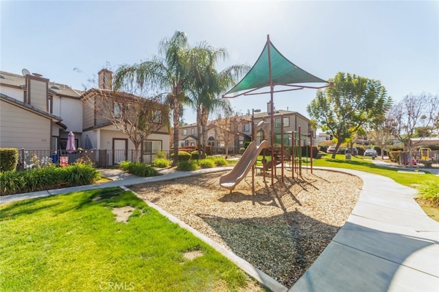 community playground featuring a yard, fence, and a residential view