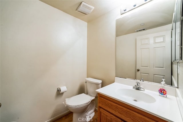 half bathroom featuring visible vents, toilet, and vanity