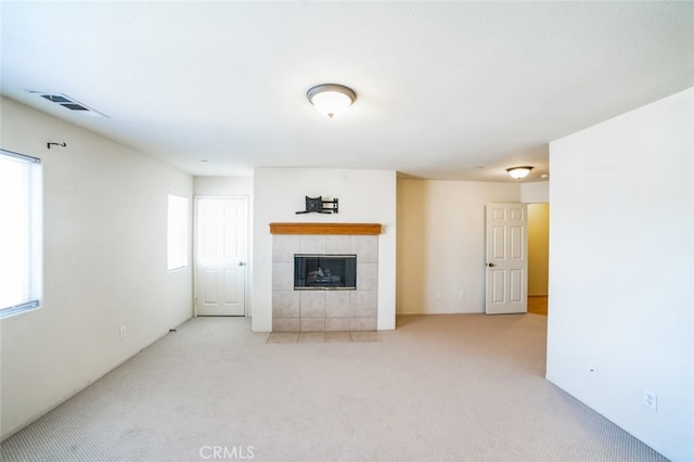 unfurnished living room with carpet, visible vents, and a tile fireplace