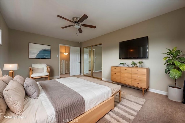 bedroom featuring a closet, light carpet, baseboards, and a ceiling fan