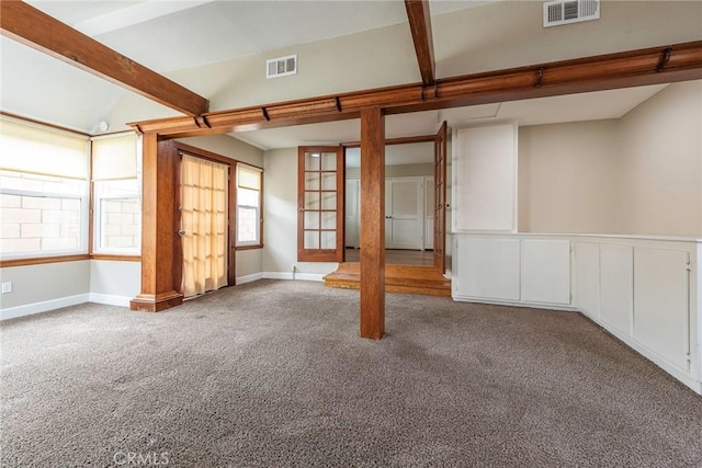 carpeted spare room with visible vents, vaulted ceiling with beams, and baseboards