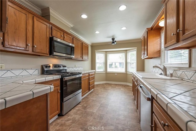 kitchen with a sink, stainless steel appliances, brown cabinets, and tile counters