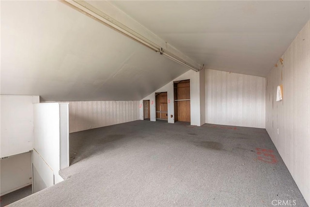 bonus room featuring vaulted ceiling with beams, wood walls, and carpet floors