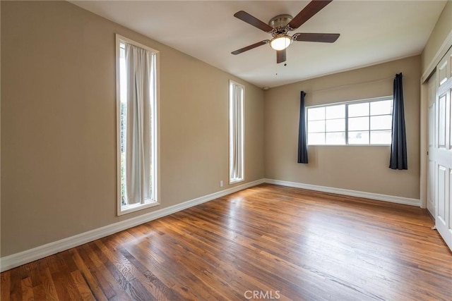 unfurnished bedroom with a ceiling fan, wood finished floors, baseboards, and a closet