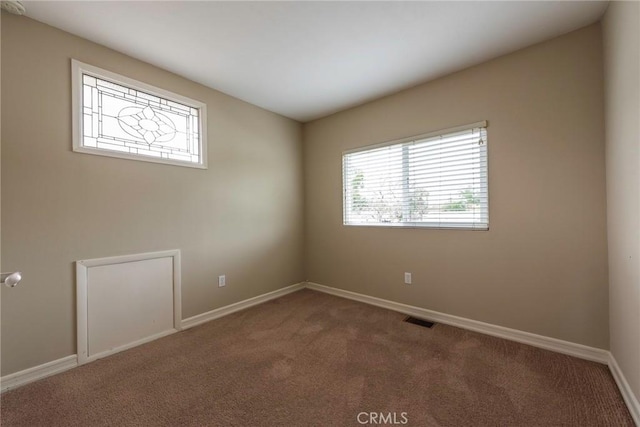 empty room with visible vents, baseboards, and carpet