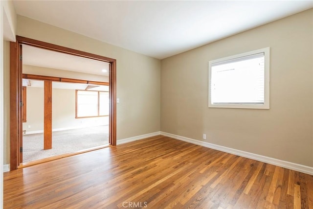 spare room featuring baseboards and light wood finished floors