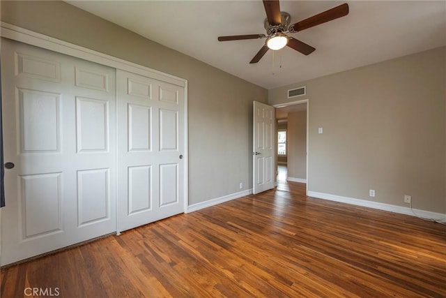 unfurnished bedroom featuring visible vents, baseboards, wood finished floors, a closet, and a ceiling fan