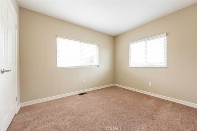 spare room featuring baseboards, carpet floors, and visible vents