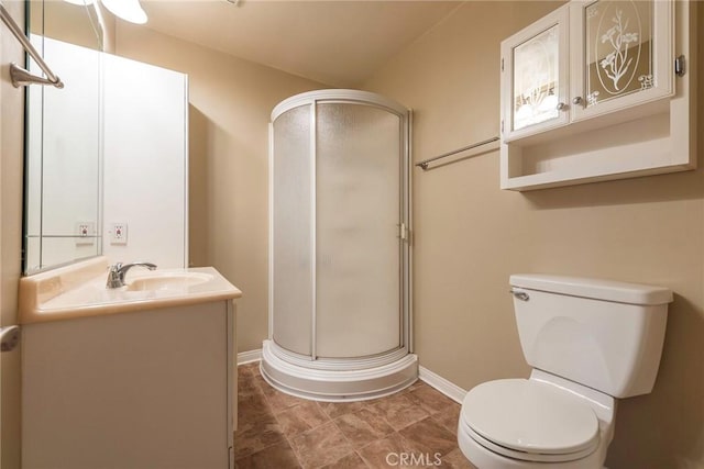 full bathroom with vanity, a shower stall, toilet, and baseboards