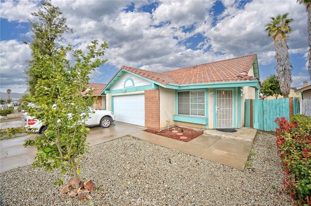 view of front of house with stucco siding, a tile roof, fence, concrete driveway, and an attached garage