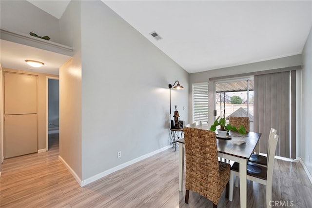 dining area featuring visible vents, baseboards, lofted ceiling, and light wood-style flooring