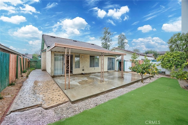 rear view of house with a patio, a yard, a fenced backyard, and stucco siding