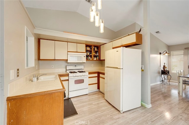 kitchen with visible vents, tile counters, vaulted ceiling, white appliances, and a sink