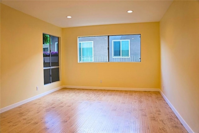 empty room with recessed lighting, wood finished floors, and baseboards