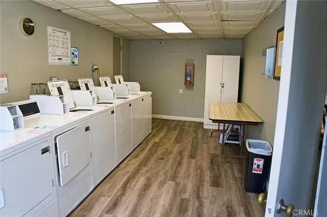 shared laundry area featuring an ornate ceiling, washing machine and dryer, concrete block wall, baseboards, and dark wood-style flooring