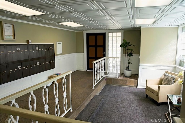 hallway featuring mail area, an ornate ceiling, and wainscoting