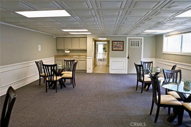 dining area featuring a wainscoted wall, an ornate ceiling, visible vents, and dark carpet