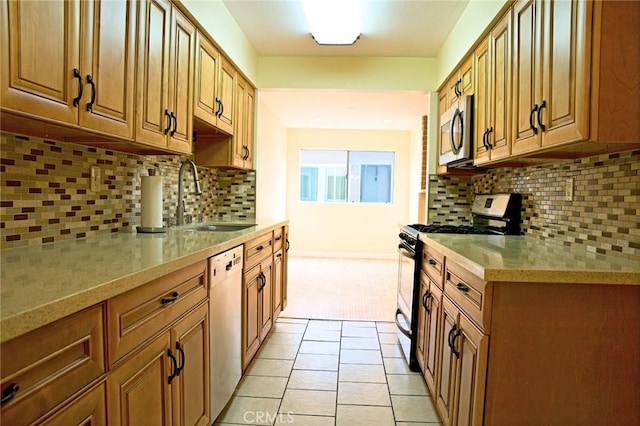 kitchen featuring tasteful backsplash, light countertops, light tile patterned floors, stainless steel appliances, and a sink